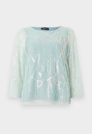 Bluză transparentă de culoare albastru deschis, cu mâneci lungi, având broderie cu meduze iridescente și paiete, decolteu rotund și croi lejer.
