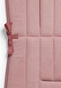 Rosa kviltad kudde med en mjuk, texturerad yta. Har ett smalt band och en rosett detalj på sidan som förbättrar säker fästning.