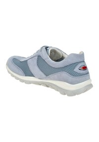 Zapatilla de ante azul claro con paneles laterales de malla, suela de goma blanca, forma redondeada y un acento de logotipo característico en el talón.