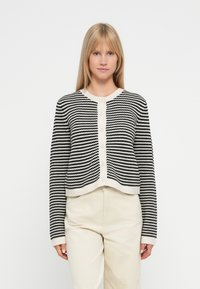 Cardigan a righe bianche e nere con design corto, scollatura rotonda e chiusura con bottoni frontali. Realizzato in materiale lavorato a maglia.