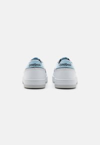 Fehér bőr sportcipők világoskék díszítéssel, sima felülettel és strapabíró gumitalppal. Reebok logó a saroknál.