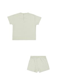 Top de algodón verde claro de manga corta con tres botones en la parte posterior y pantalones cortos ajustados a juego, que presentan una cinturilla elástica y una textura lisa.