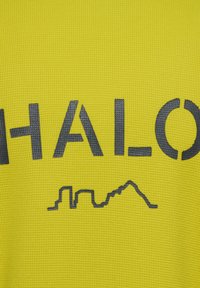Gul textil med en texturerad yta. Har fet svart stil som stavas "HALO" och en tunn linjeteckning av ett landskap under texten.
