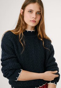 Maglione lavorato a maglia blu navy con un design a treccia testurizzato, collo alto e bordi scallop bianchi a contrasto sui polsini e sull'orlo.