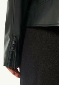 Czarna skórzana kurtka z detalem na mankiecie zapinanym na zamek, w zestawieniu z teksturowanym czarnym ubraniem. Skoncentrowano się na gładkim materiale i eleganckich elementach wzorniczych.