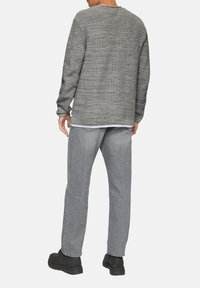 Grijze gebreide trui met een gestructureerde afwerking, relaxte pasvorm en lange mouwen. Gecombineerd met lichtgrijze jeans en zwarte chunky laarzen.