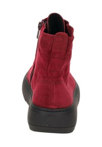 Rote Wildleder-Ankle-Boots mit einer schwarzen Gummisohle, Reißverschluss und einer strukturierten Oberfläche im oberen Bereich. Mit einem Ziehschlaufe auf der Rückseite.