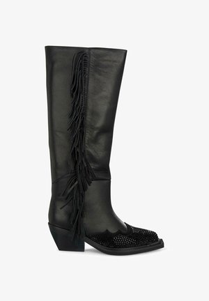Bota de cuero negro hasta la rodilla con detalle de flecos, tejido texturizado en la puntera y tacón grueso. Presenta acentos de diseño en forma de ondas.