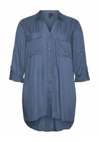 Chemise bleu clair à manches longues en tissu doux. Dotée de deux poches poitrine, d'une patte de boutonnage à l'avant et de manches retroussables. Ourlet arrondi.