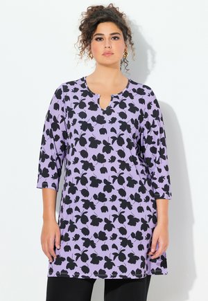Lila Tunika mit schwarzem Blumenmuster, runder Ausschnitt mit einem Schlitzdetail und Dreiviertelärmeln. Weicher, elastischer Stoff.