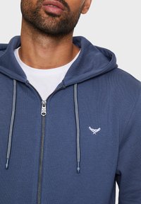 Navyblaue Zip-Hoodie mit Kapuze und Kordelzug, aus leichtem Stoff, mit kleinem gesticktem Emblem auf der linken Brust.