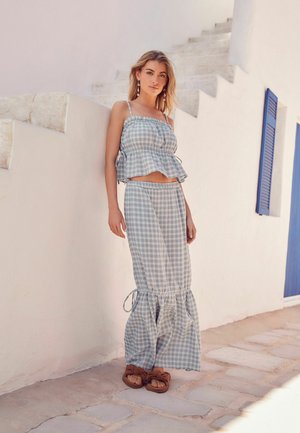 Blau-weißes Karo-Zweiteiler-Set mit einem Peplum-Oberteil mit verstellbaren Trägern und einem langen Rock mit rüschenförmigem Saum und seitlichen Bindebändern.