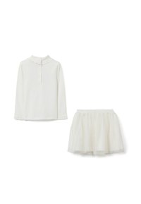 Top bianco a maniche lunghe con colletto a balze e bottoni abbinato a una gonna a strati in tulle bianco con vita elastica.