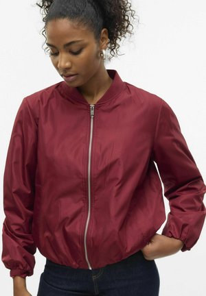 Giacca bomber bordeaux con zip frontale, colletto a costine e polsini elasticizzati. Realizzata in materiale leggero e liscio, offre una vestibilità comoda.