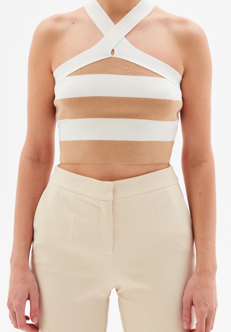 Top corto a rayas en tonos beige y blanco con diseño de halter. Presenta un detalle de abertura en el escote y una textura de punto ajustada.