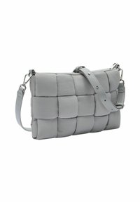 Borsa a tracolla grigia imbottita con design a quadrati trapuntati e tracolla regolabile con ganci metallici su sfondo bianco.