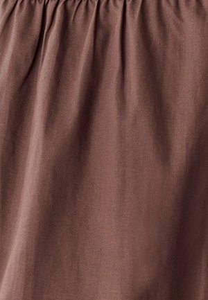Tissu marron à la texture lisse et au haut froncé. Le matériau semble léger avec un subtil éclat, présentant des drapés doux et fluides.