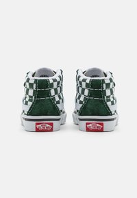 Zapatillas altas Vans de cuadros verdes y blancos, con material de gamuza, cuello acolchado, cordones blancos y etiqueta de logo roja en el talón.