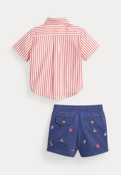 Κόκκινο και λευκό κάθετα ριγωτό κοντομάνικο πουκάμισο συνδυασμένο με μπλε σορτς σκαφάτου θέματος με κεντημένα σχέδια και τσέπες με κουμπιά.