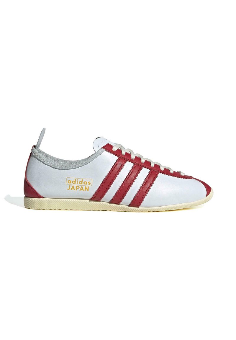 Weiße Leder-Sneaker mit roten Akzenten und drei Streifen, ausgestattet mit einem grauen Kragen und einer strukturierten Gummisohle. "adidas JAPAN"-Logo sichtbar.