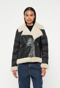 Schwarze Lederjacke mit Polsterung und einem Kragen sowie Manschetten aus cremefarbenem Kunstfell; ausgestattet mit Reißverschlusstaschen und einem taillierten Design.