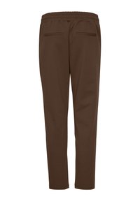 Pantaloni sport maro cu talie elastică și două buzunare în partea din spate. Realizați dintr-un material moale cu o textură netedă. Conici la gleznă.