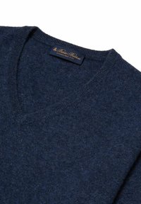 Marineblauwe v-halstrui van zacht breimateriaal met geribde manchetten en een gladde textuur. Bevat een label met gouden letters.