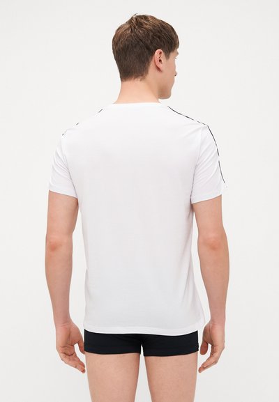 White crew neck t-shirt made of cotton, featuring short sleeves and black trim along the shoulders, fitted cut, and smooth texture.