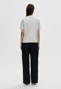Graues T-Shirt mit kurzen Ärmeln und rundem Halsausschnitt, kombiniert mit marineblauen weiten Hosen, die eine glatte Stoffstruktur und eine entspannte Passform zeigen.