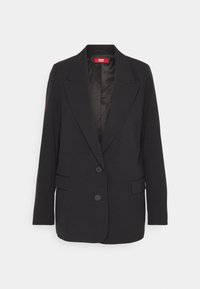 Blazer noir en tissu texturé. Il dispose d'un col cranté, de deux boutons à l'avant et de deux poches latérales. L'intérieur doublé ajoute un contraste.