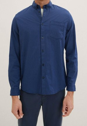 Camisa de botones azul marino con un pequeño patrón de cuadros, un bolsillo en el pecho y mangas largas con puños abotonados. Material de algodón.