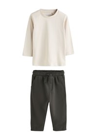 T-shirt crème à manches longues avec col ras du cou, associé à un pantalon gris foncé à taille élastique, avec poches latérales et cordon de serrage à l'avant.