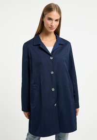 Navyblauwe jas van gladde stof, met een klassieke kraag, vijf knopen en zijzakken. Perfecte pasvorm met lange mouwen.