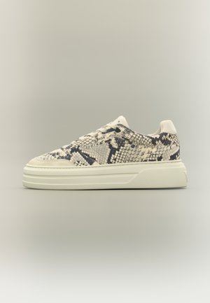 Sneaker basse con suola bianca e motivo in pelle di serpente beige-nera sulla tomaia, vista di lato su uno sfondo chiaro.