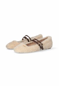 Beige, zachte instappers met twee donkerbruine leren banden en goudkleurige gespen, met een zachte textuur en een klein decoratief embleem op de neus.