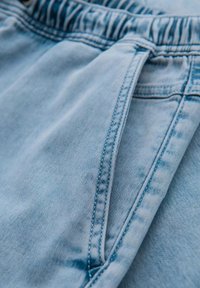 Pantalones cortos de mezclilla azul claro con cintura elástica, que cuentan con bolsillos laterales y detalles de costura visibles para mayor durabilidad.