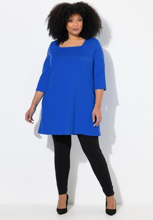 Blå tunika med firkantet udskæring, trekvartærmer, parret med sorte leggings. Glat tekstur, knælængde design og en afslappet pasform.