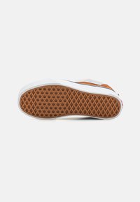 Gummisål til sneakers med et struktureret brunt mønster, hvide kanter og orange samt marineblå accenter på den øverste del.