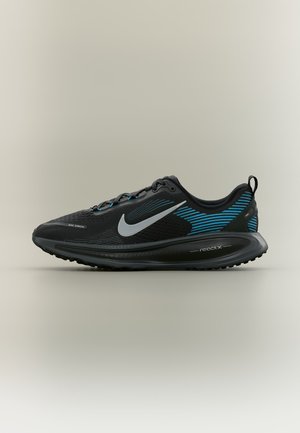 Chaussure de course Nike React noire avec des bandes bleues, un swoosh gris et une semelle amortissante, vue de profil sur fond neutre.
