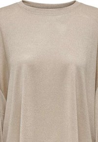Maglione beige realizzato in tessuto morbido e testurizzato. Presenta un collo rotondo e una silhouette morbida con spalle abbassate.