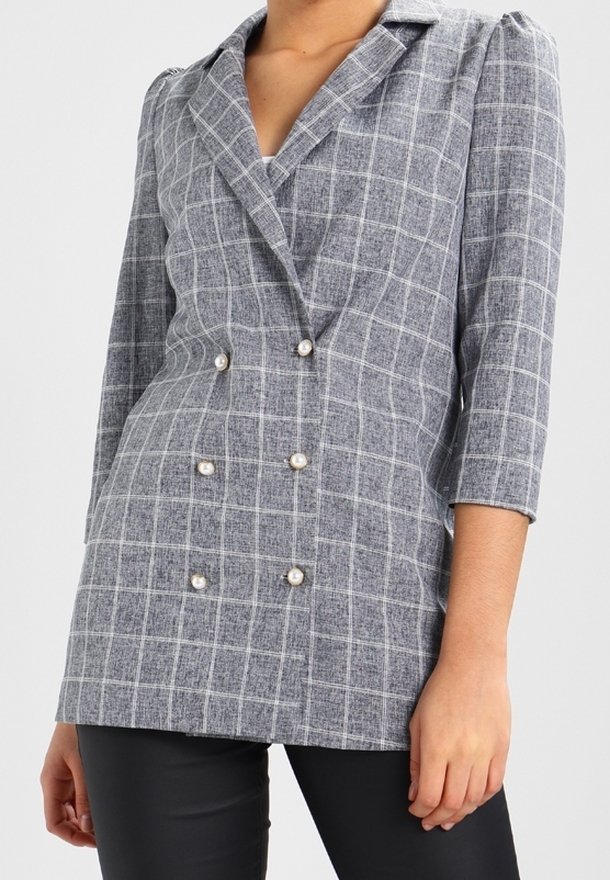 Dubbelknäppt kavaj i grå och vit rutmönster, med pärlknappar och trekvartslånga ärmar, tillverkad av en strukturerad tyg.