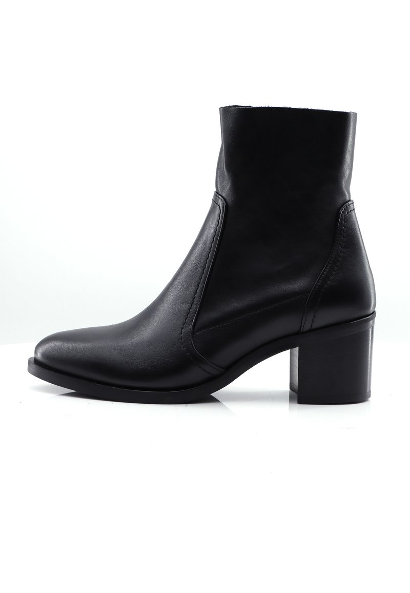 Schwarze Leder-Stiefelette mit spitzem Zehenbereich, schlankem Design, elastischen Seitenpaneelen und blockigem Absatz. Glatte Textur und minimale Nähte.