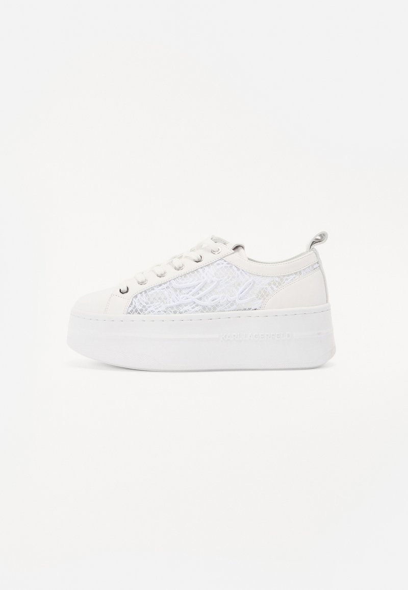 Sneaker bianco con piattaforma e pannello laterale in argento testurizzato, lacci piatti e logo sul tallone. Materiale liscio, design della punta arrotondata.