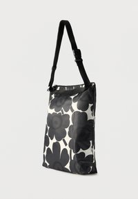 Sort-hvidt blomsterprintet taske med rektangulær form, lavet af glat stof, med justerbar rem og lynlås øverst.
