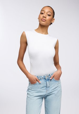 Body bianco senza maniche con finitura liscia, abbinato a jeans a vita alta di colore azzurro chiaro, dotati di tasche frontali e di una vestibilità rilassata.