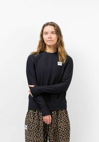 Schwarzes Langarmshirt mit gerippter Textur und rundem Halsausschnitt, mit einem gestickten Logopatch auf der linken Brust.