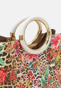Blommig och leopardmönstrad tygkasse med vita och gyllene cirkulära handtag. Har levande färger och intrikata blad- och blommönster på syntetiskt material.