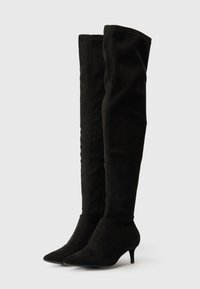 Mustad üle põlve saapad, valmistatud pehmest mokasiinist, terava nina ja peene kõrge kontsaga, sujuva disainiga ning nähtava riistvarata.