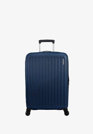 Valigia di dimensioni cabin in blu scuro, caratterizzata da una superficie rigata testurizzata, manico telescopico e quattro ruote girevoli per una facile manovrabilità.