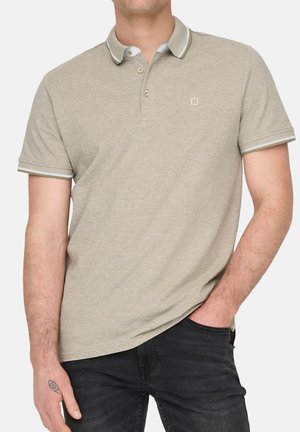 Polo en beige clair avec une texture douce, doté d'une patte de boutonnage à deux boutons, d'un col contrastant et d'un logo subtil sur la poitrine.